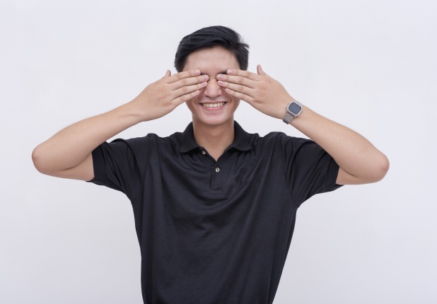 Young man smiling and covering his eyes