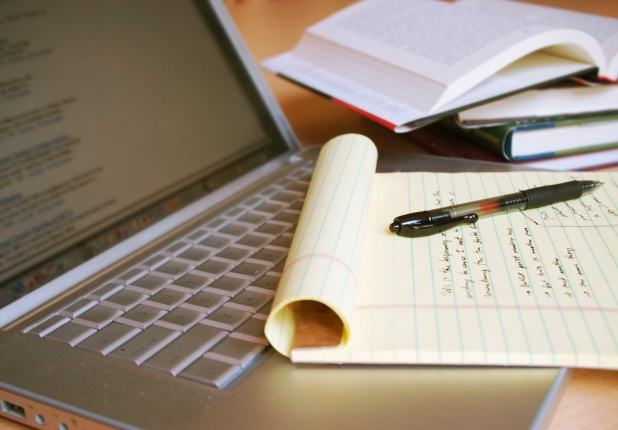 Laptop computer with yellow legal pad containing notes