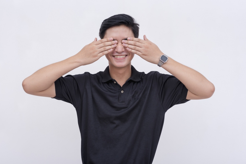 Young man smiling and covering his eyes