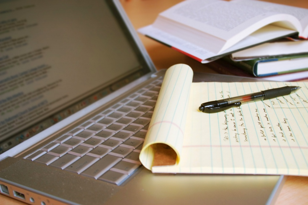 Laptop computer with yellow legal pad containing notes